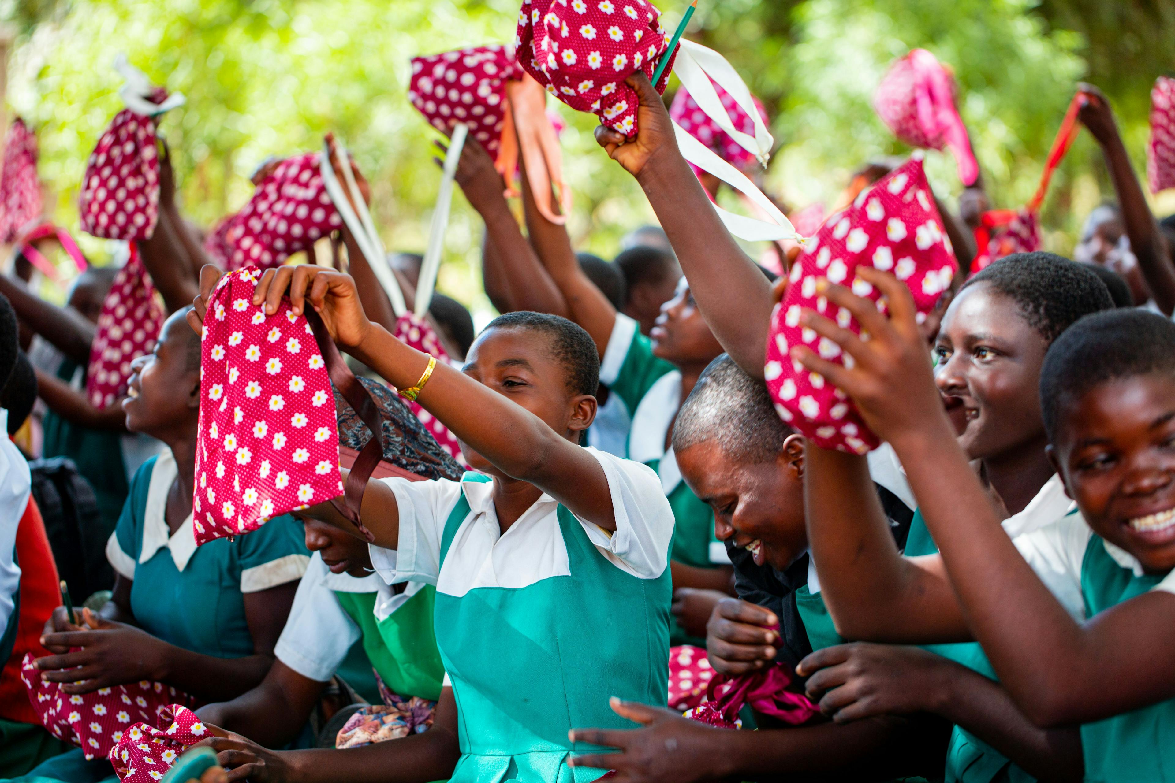 Young women in Africa celebrate as they receive new pad kits to help with menstrual hygiene.