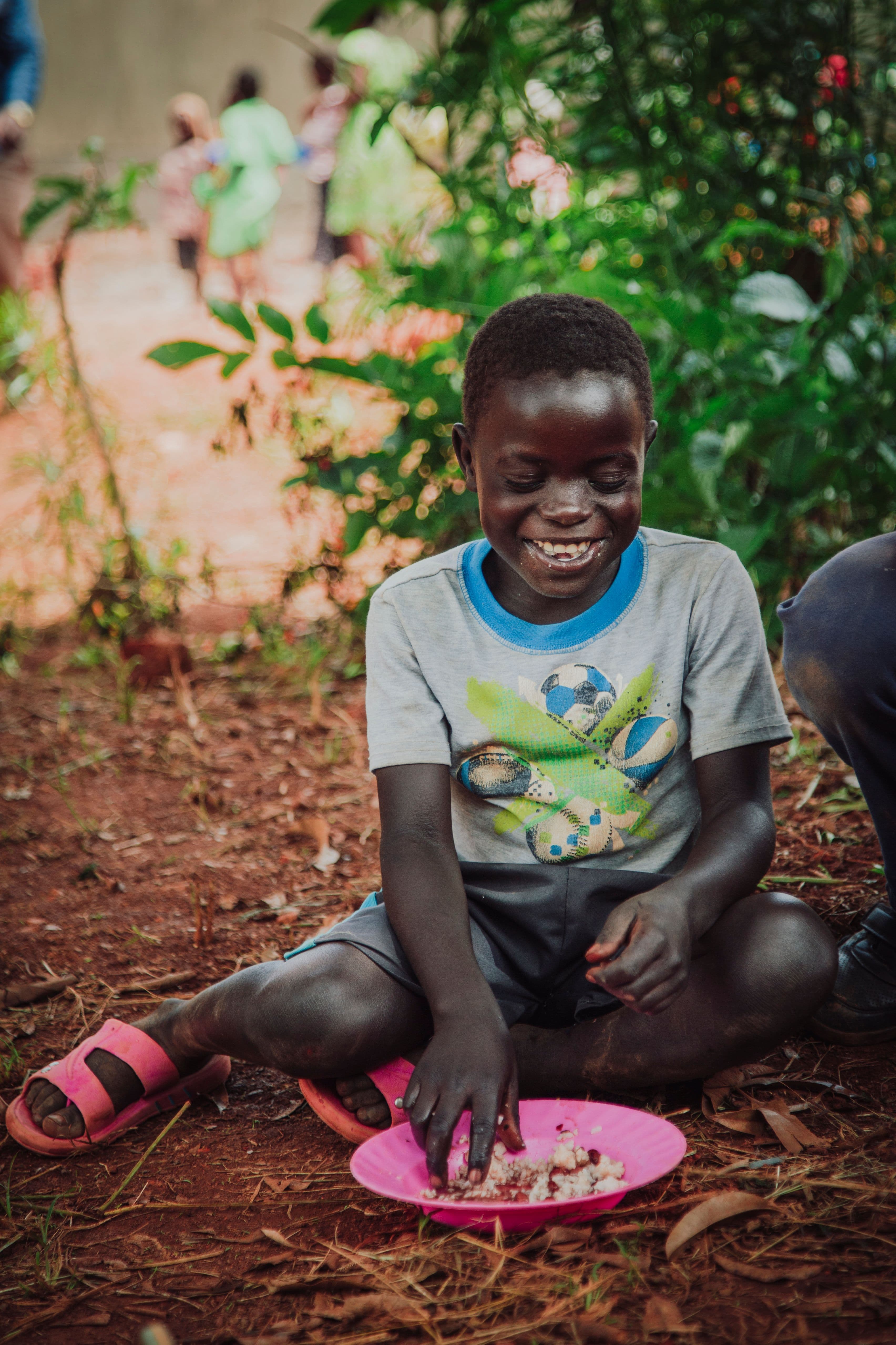 Ugandan boy eats outside under a tree